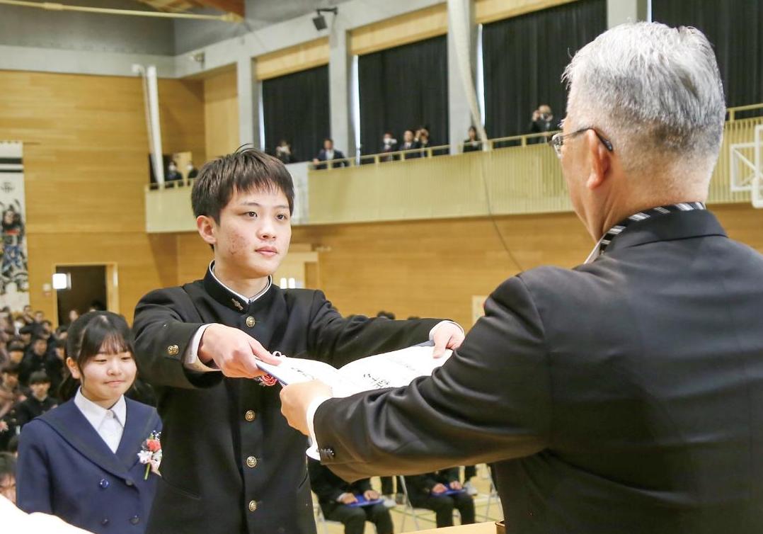 中学生が卒業証書を受け取っている風景