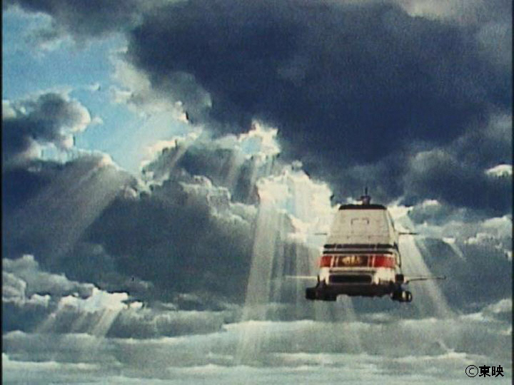 雲の間から幾筋もの神々しい光が降り注ぐ「天使の梯子」を背景に、白い機体に赤いラインが入った戦艦が、安定した姿勢で空中をこちらへ向かって直進している写真