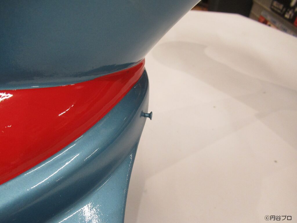 円谷プロ作品の大型戦闘機「スカイホエール」のミニチュアで、青い機体と赤い塗装の境界線を極至近距離から撮影しており、曲面に沿った箇所にテグス糸を結ぶ小さく突き出したボルト部分を捉えた写真