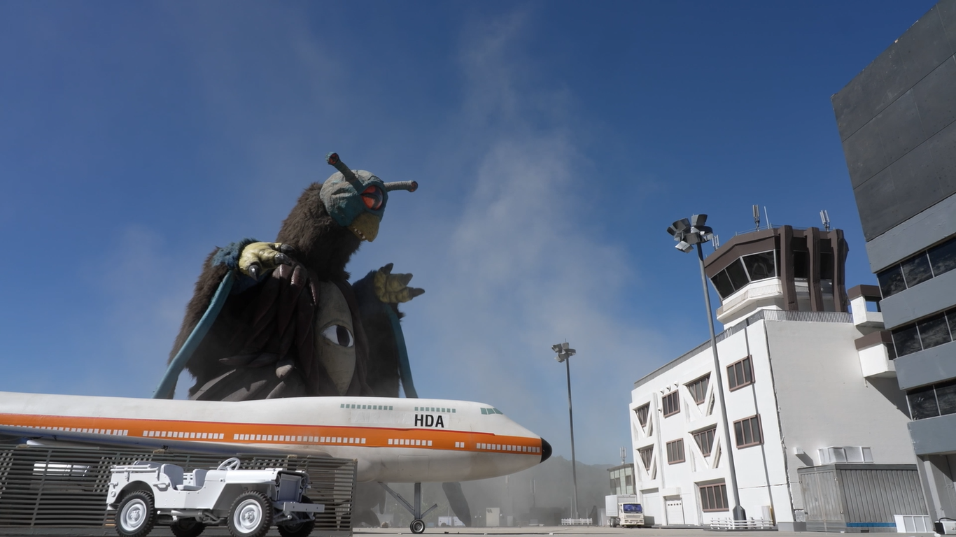 怪獣フェザーロンが空港の管制塔に迫っている様子