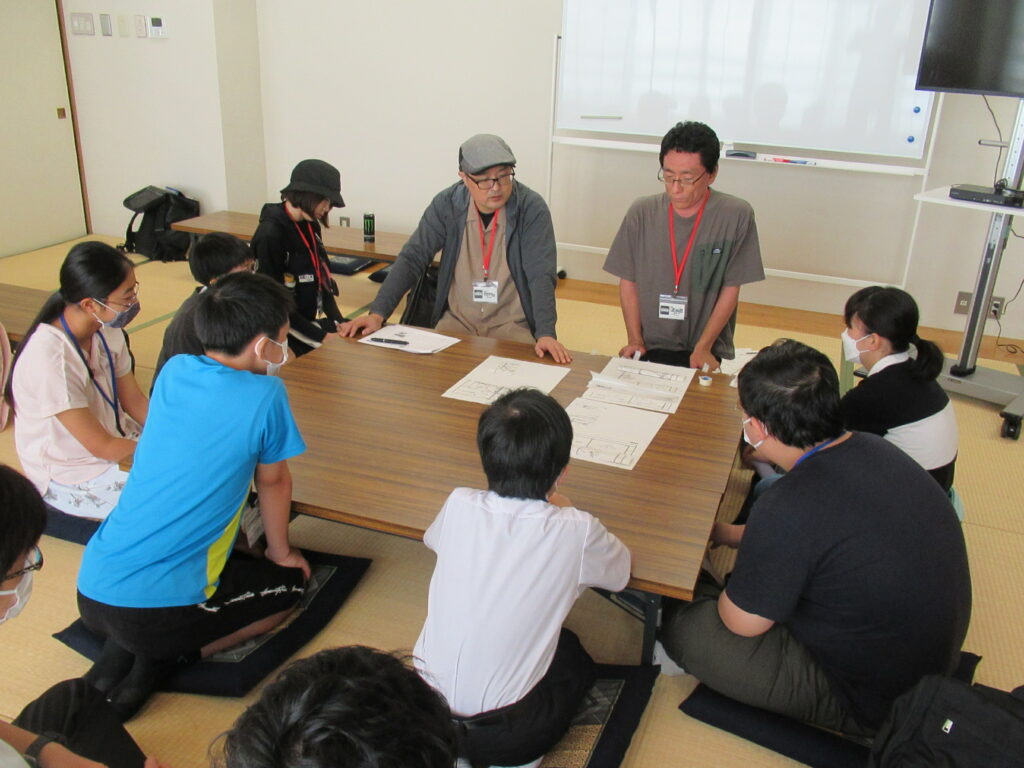 畳敷きの部屋で、中央に置かれた木製の長机を囲み、講師の話を塾生たちが熱心に聞いている写真