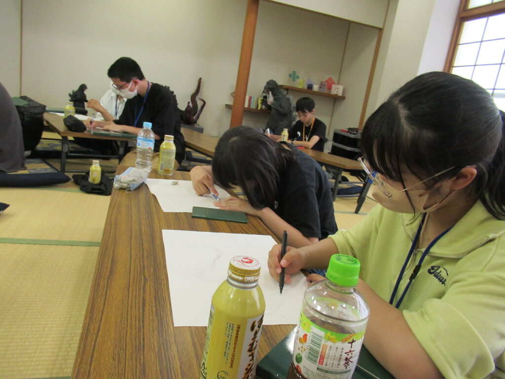 畳の敷かれた和室の机に座り、数名の塾生が真剣な表情で白い紙に記載している写真