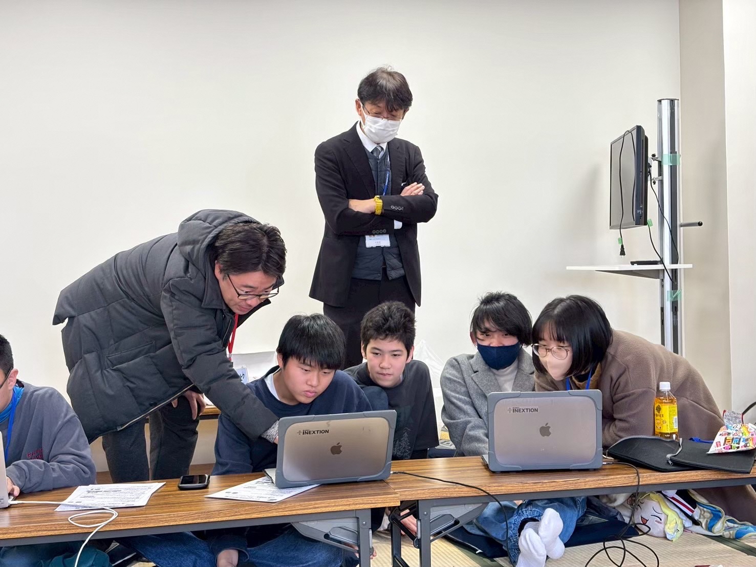 パソコンで映像編集をする塾生たちが、講師から直接指導を受けている様子