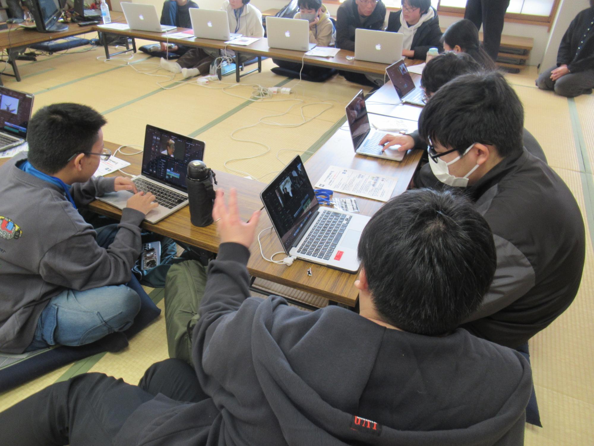 パソコンで映像編集をしている塾生に講師が横に座ってアドバイスをしている様子