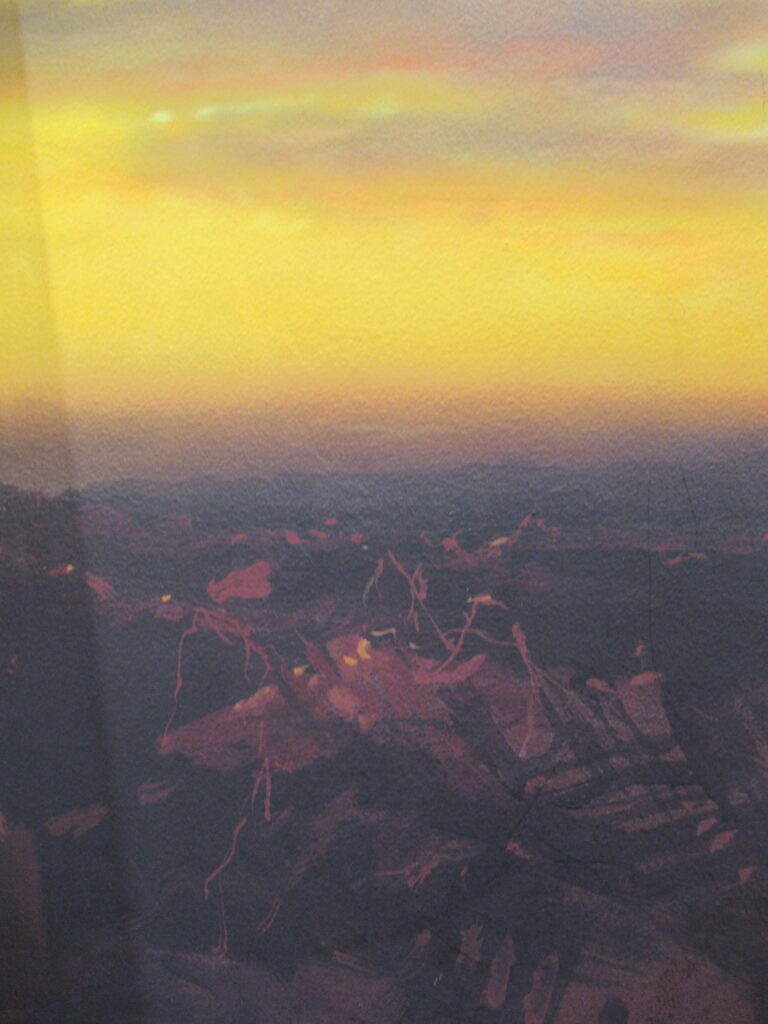 黄金色に輝く空が広がり、下部には暗い影に包まれた複雑な地形や建物のシルエットが重厚な筆致で描かれた背景画の写真