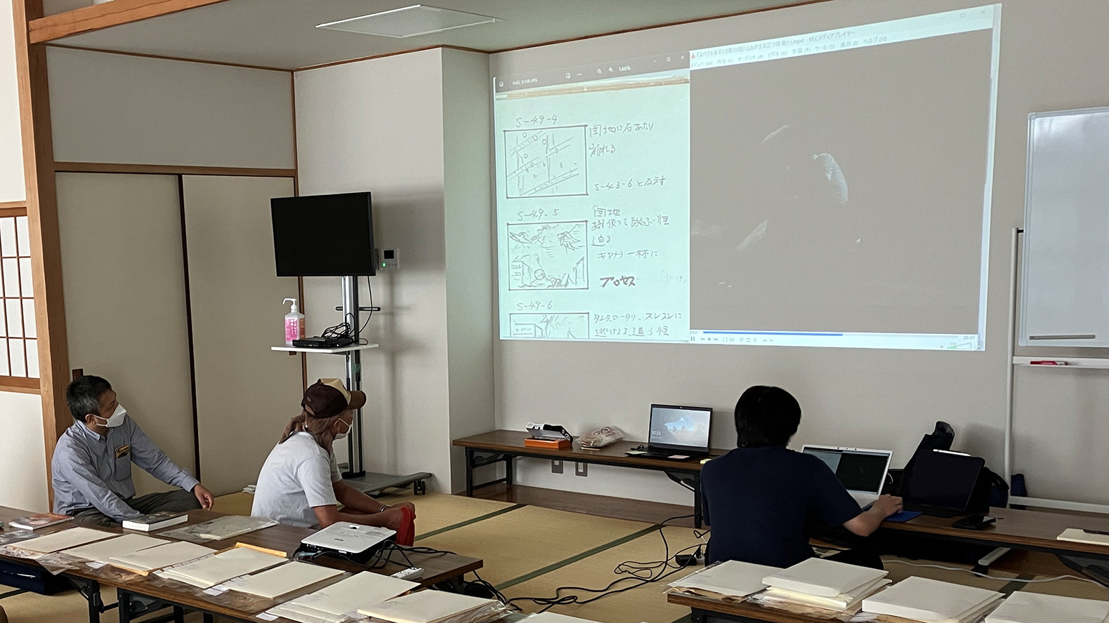 矢島監督の絵コンテ資料を壁に大きく投影して調査作業を行っている様子の写真