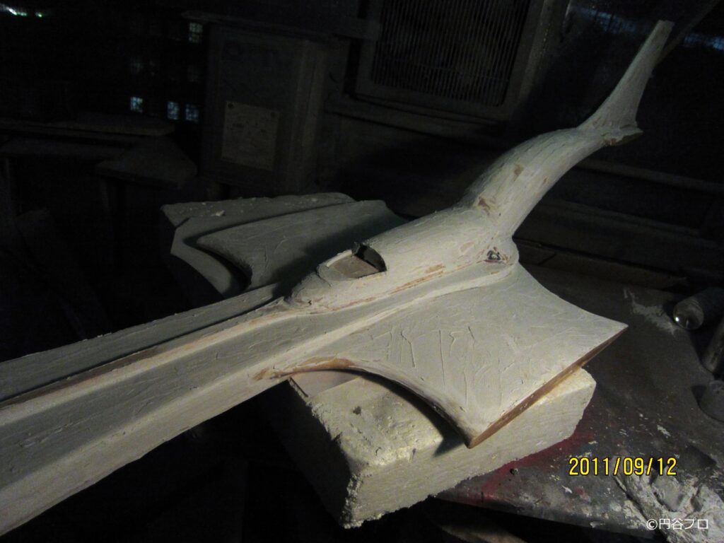 暗い作業場の一角に、台座に載せられた大型戦闘機をが修復処置されている途中の写真