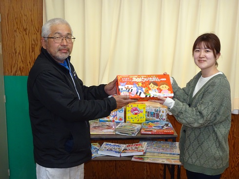吉田さんが職員に絵本を手渡す様子の写真