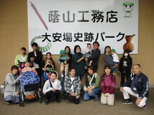 「蔭山工務店大安場史跡パーク」と書かれている壁を背景に親子や関係者が2列に並び記念撮影を行っている様子の写真