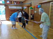 広いスペースで、青いテープが床に貼られ、父親と一緒にゴールするのを見守っている様子が写された写真