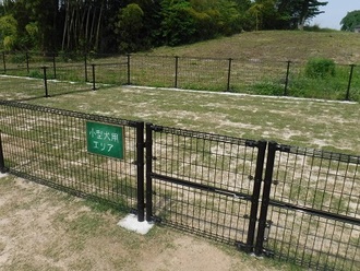 「小型犬用エリア」と書かれた看板が設置された、黒い金属製のフェンスで仕切られたドッグランの写真