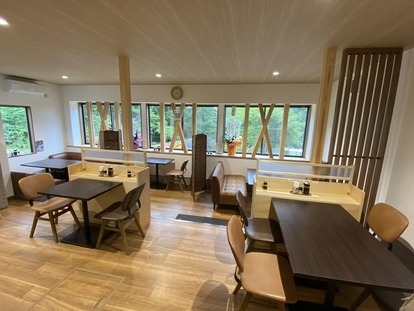 明るい色調の木材を使用した床や柱の室内に、ゆったりと配置されたダークブラウンのテーブル席やキャメル色のソファ席が並ぶ、清潔感のある開放的な店内の写真