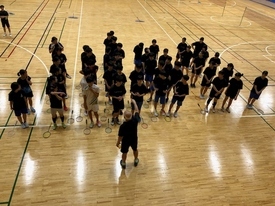 指導者が整列して並んでいる学生たちの前に立ち説明している様子を、2階の観客席から撮影した写真