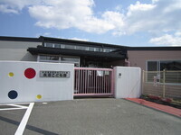 白い壁に赤や青の丸い模様が描かれた可愛らしい外構と、ピンク色の門扉が印象的な「長沼こども園」の入り口付近を正面から捉えた写真