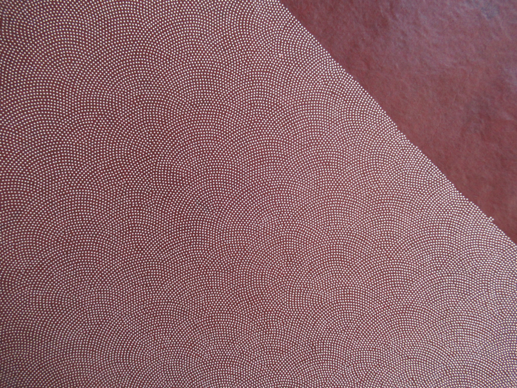 えんじ色をベースに、微細な白い点で波のような模様が施された生地のクローズアップ写真