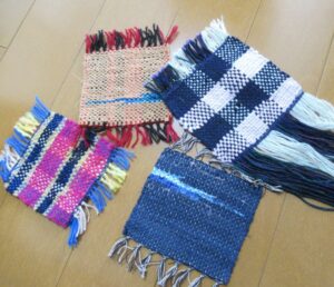 木の床の上に四枚の四角い手織り布が鮮やかな色糸で織られ微妙な風合いと異なる柄を見せながら整えて置かれている写真