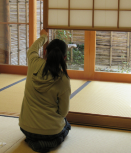 畳に正座して障子戸の開け方の作法を練習している参加者の女の子の後ろ姿の写真