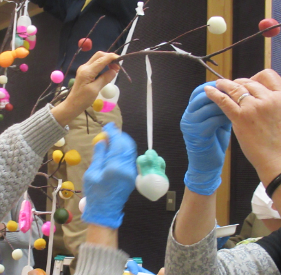 枝に色とりどりのだんご飾りを取り付けている様子の写真