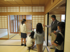 和室で数人の子どもが男性の説明に耳を傾けながら障子の造りを見学している様子を写した写真
