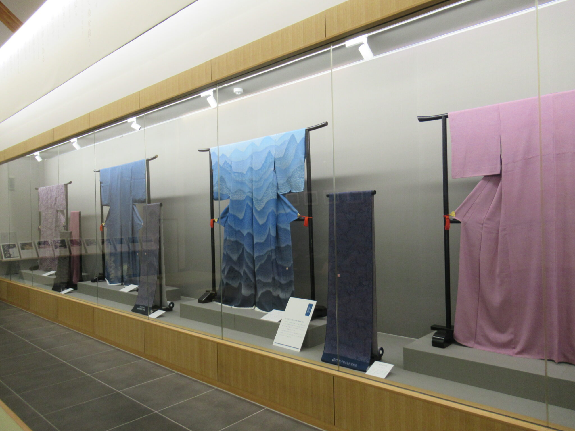 ガラスケース内に青や紫の着物や反物が整然と展示されている写真