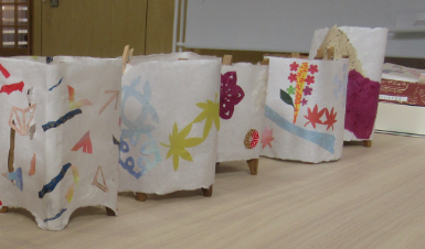 糸巻きに色とりどりの切り紙を貼った和紙を巻いた行灯が5つ、テーブルの上に並んでいる写真