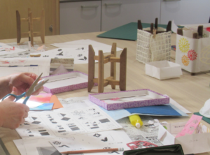 色とりどりの紙や型紙が広がる作業台でハサミを使い制作を進める手元の様子を写した写真