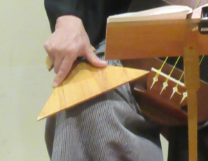 大きな撥を手で押さえ、膝の上に添えられている写真