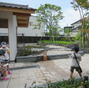 和風の庭園で数人の子どもがノートを手に景観を観察している様子の写真