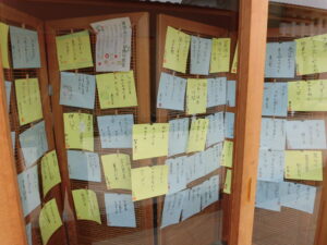 木枠のパーティション一面に、俳句を書いた黄色と水色の正方形の紙が隙間なく貼られた展示の写真