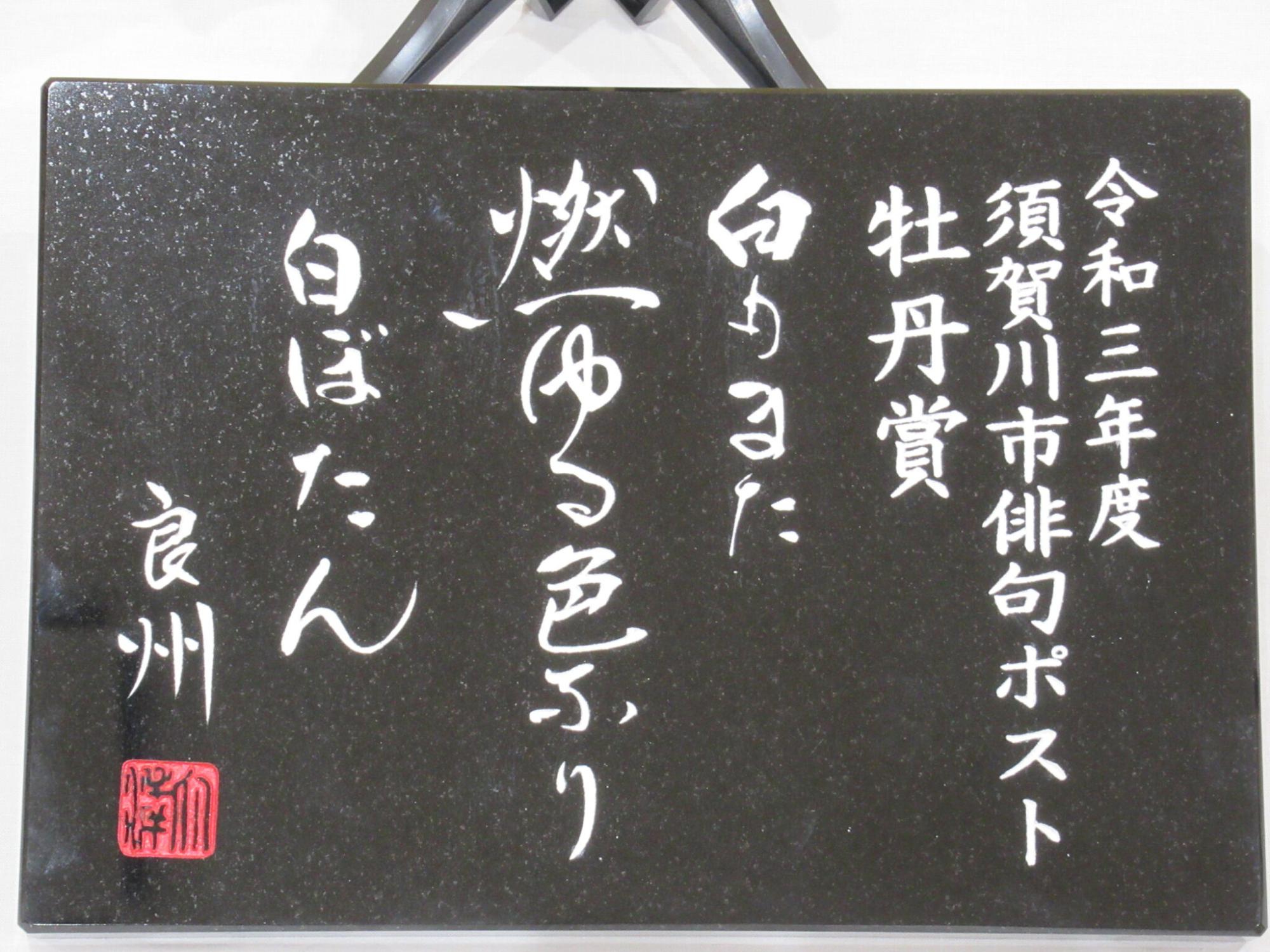 左に「令和三年度 須賀川市俳句ポスト 牡丹賞」と記され、中央に「白もまた 燃ゆる色ふり 白ぼたん 良州」と手書き風の白い文字が刻まれた黒い石板の写真
