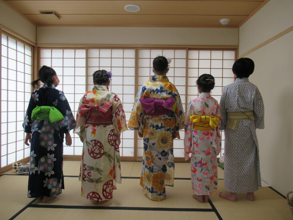 着付けが終わり、色とりどりの帯を締めた浴衣姿の男女の子どもたちが横一列に並んだ後ろ姿の写真