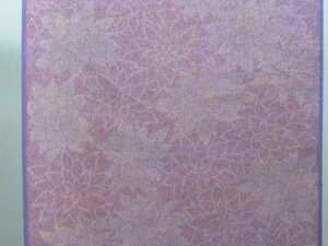 桃色の布地全体に細かな線で描かれた白い花文様が重なり、柔らかな色彩と繊細な意匠が広がる布地の写真