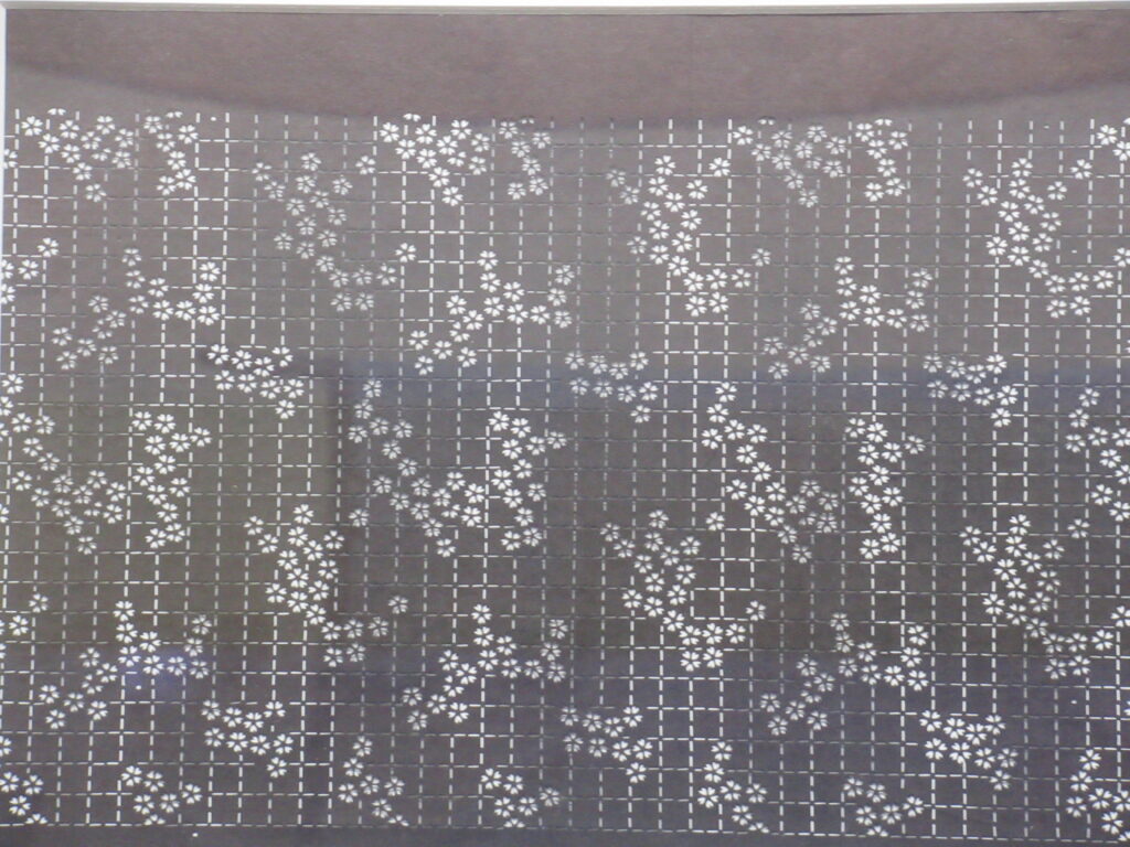 グレーの生地に白で格子模様と小さな白い花文様が不規則に配置された生地のクローズアップ写真