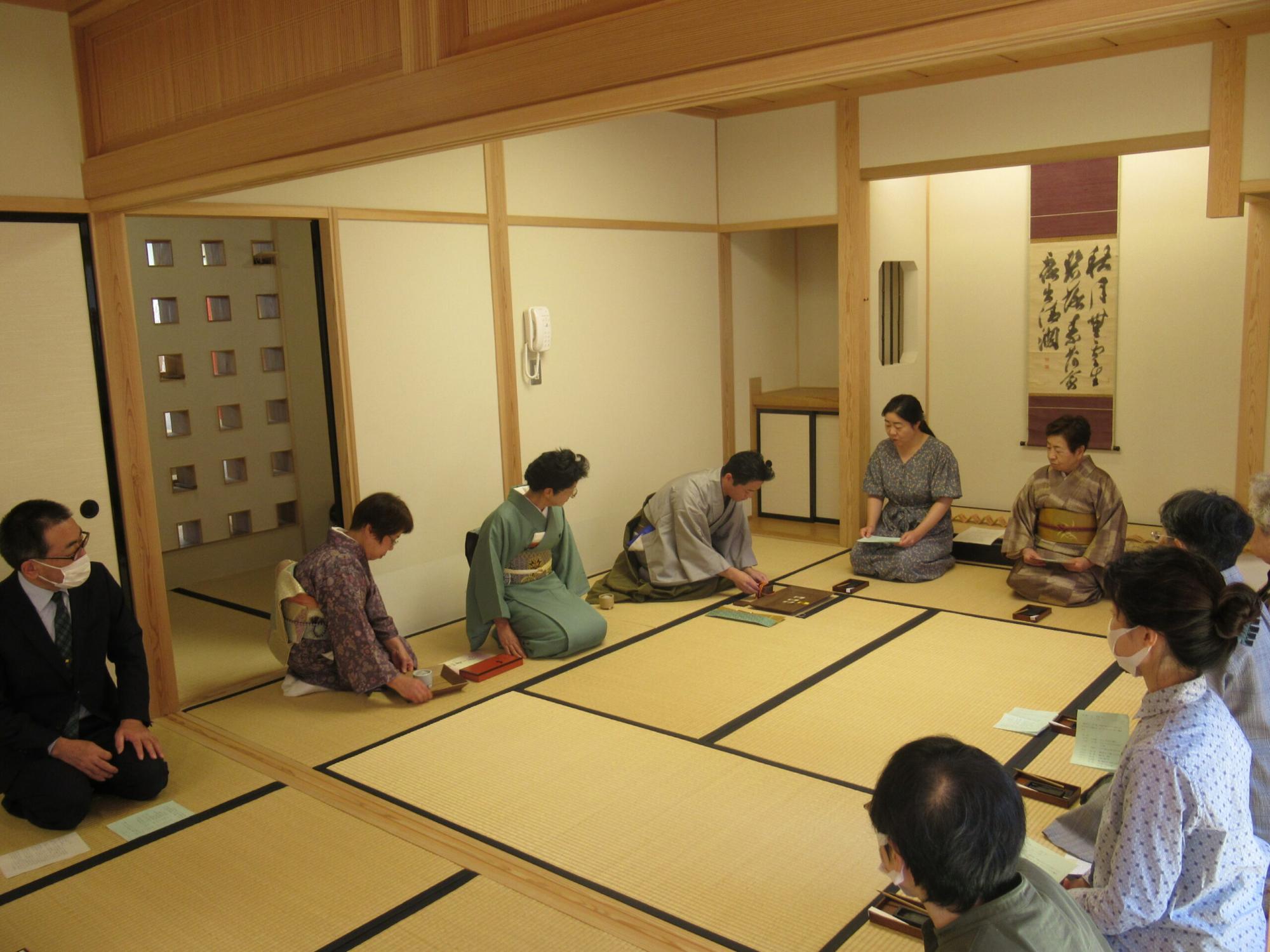 和室の畳の上でコの字型に座った、和装や洋装の男女が香道を体験している様子の写真