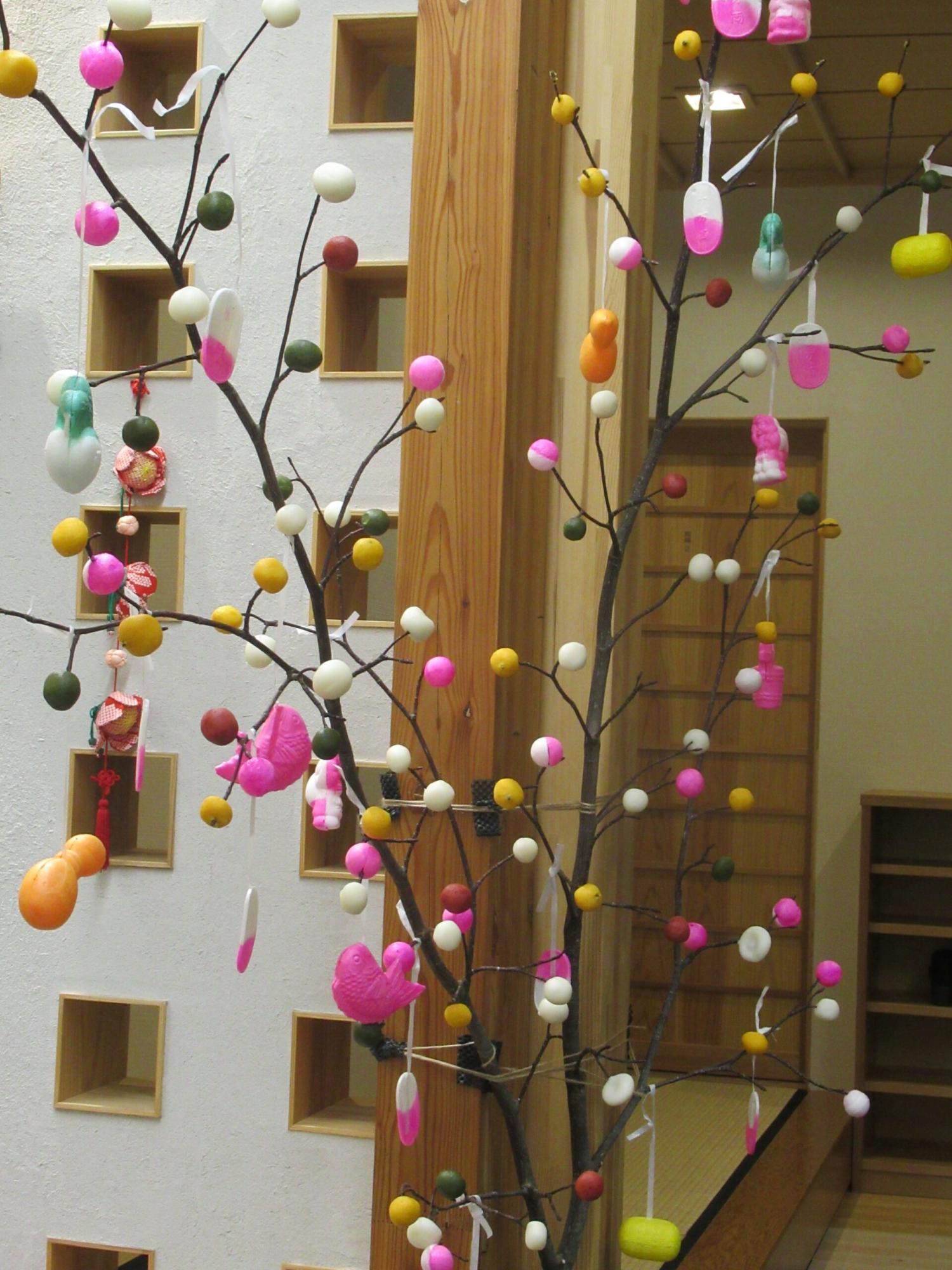 枝に白・桃・黄・緑などのだんごがたくさん飾られ、完成しただんごさしの写真