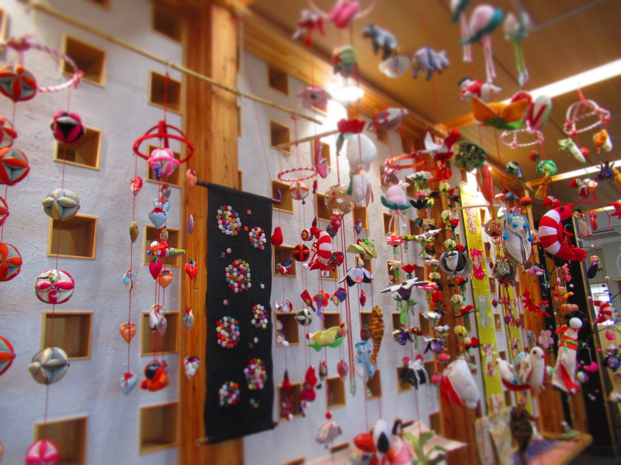 色とりどりの布細工が天井から無数に吊るされ、鳥や花など多様な飾りが温かな空間を賑やかに彩る写真