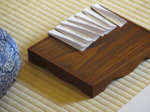 木目の美しい茶道具の盆の上に、白く細長い和紙が等間隔で丁寧に折り重ねられておかれている写真