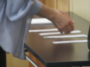 テーブルに並んだ複数の短冊に、1人の女性が手を伸ばしている様子の写真