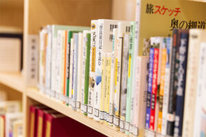 木製の本棚に様々な書籍が整然と並んでいる様子を写した写真