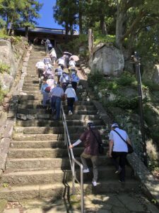 石造りの長い階段を中央の手すりをつかみながら大勢の参加者が登っている様子を下から捉えた写真